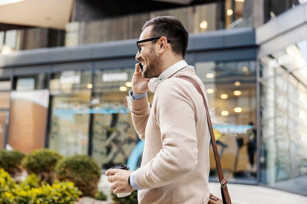 Miejski biznesmen idzie ulicą podczas rozmowy telefonicznej