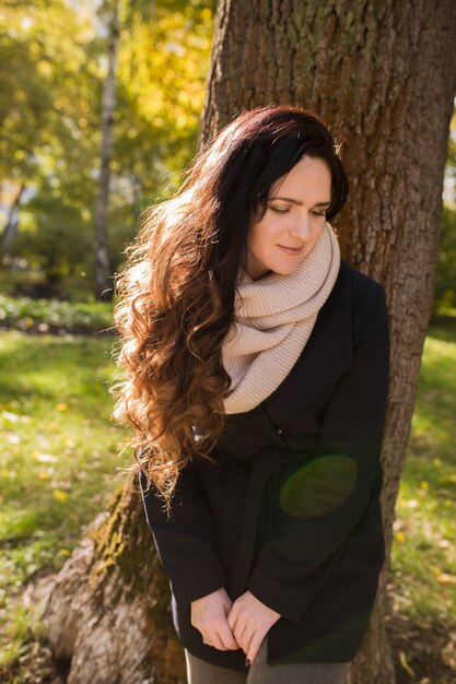 Miejski portret ładna brunetka kobieta z długimi falującymi włosami pozowanie w parku w słoneczny dzień