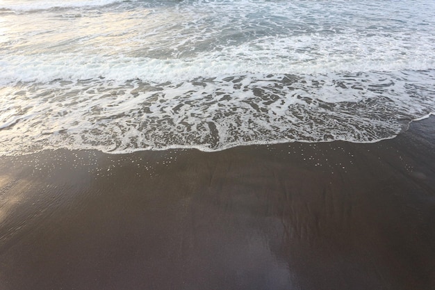 Miękka fala błękitny ocean na piaskowatej plaży. Tło.
