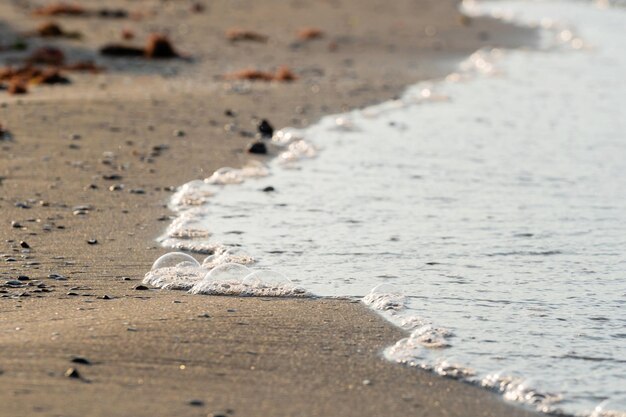 Miękka fala oceaniczna na piaszczystej plaży w czasie zachodu słońca, selektywna ostrość