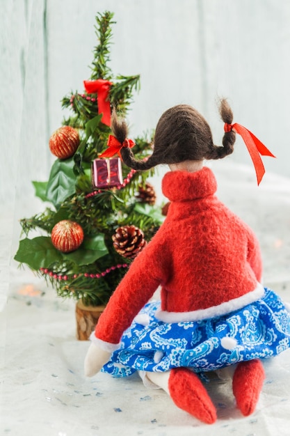 Miękka tekstylna lalka w pobliżu choinki z prezentami