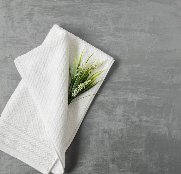 Zdjęcie miękki ręcznik z kwiatkiem w szarym ozdobnym tle stiuku. widok z góry, na białym tle