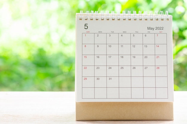 Miesiąc maj, kalendarz biurko 2022 dla organizatora do planowania i przypomnienia na drewnianym stole z zielonym tłem natury.