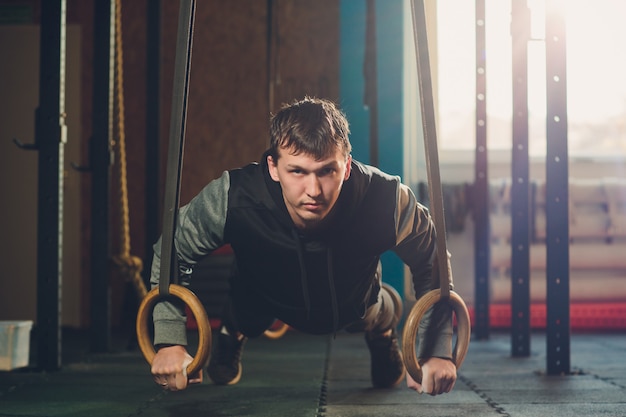 Zdjęcie mięśni ćwiczenia atletyczny mężczyzna robi intensywnemu treningowi przy gym na gimnastycznych pierścionkach.