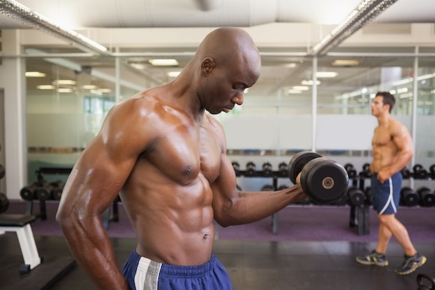 Mięśniowy mężczyzna ćwiczy z dumbbell w gym