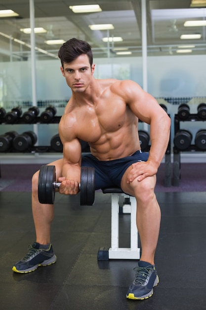 Mięśniowy mężczyzna ćwiczy z dumbbell w gym