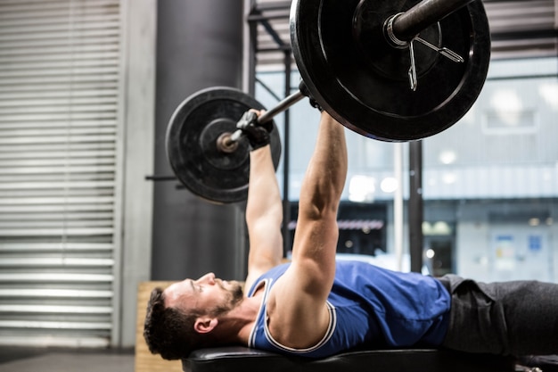 Mięśniowy mężczyzna na ławki udźwigu barbell przy crossfit gym