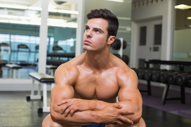Mięśniowy mężczyzna patrzeje daleko od w gym