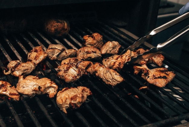 Mięso przygotowuje na grillu na czarnym tle Szef kuchni przygotowuje szaszłyk