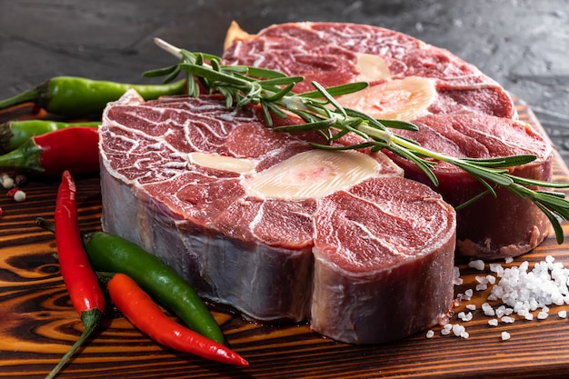 Mięso wołowe gicz cielęca pokrojone mięso na ciemnej drewnianej desce do krojenia.