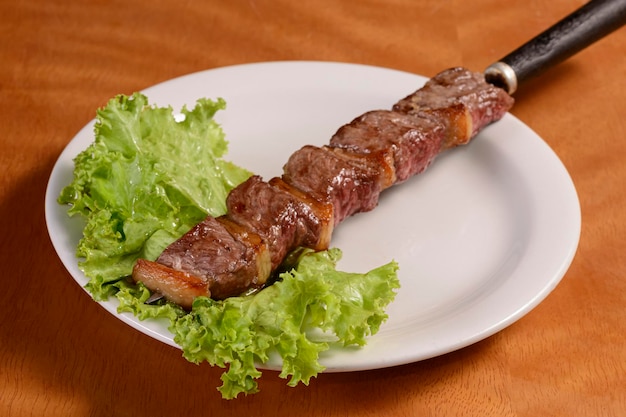 Mięso z grilla na szaszłykach Tradycyjny brazylijski kebab w białym talerzu na drewnianym stole