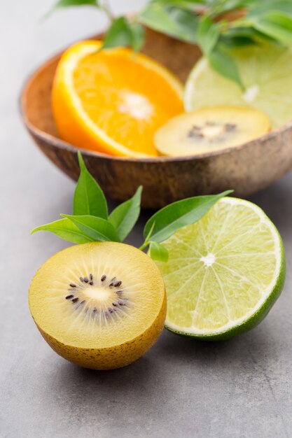 Mieszane cytrusy cytryny, pomarańcza, kiwi, limonki na szarej powierzchni.