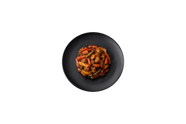 Mieszanka warzyw kukurydza marchew papryka brokuły cebula w sosie teriyaki na talerzu ceramicznym na ciemnym betonowym tle
