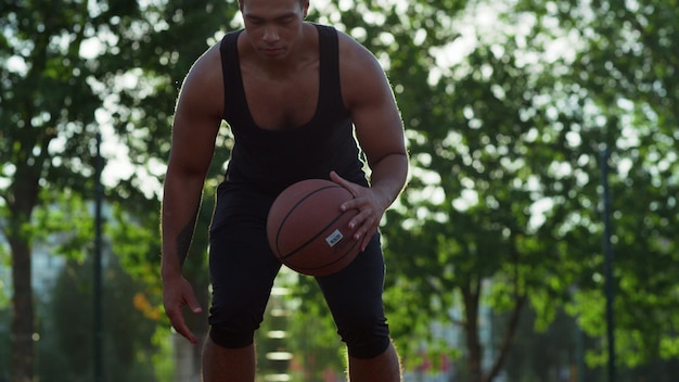 Mieszany zawodnik streetballu ćwiczący koszykówkę na sportowym placu zabaw