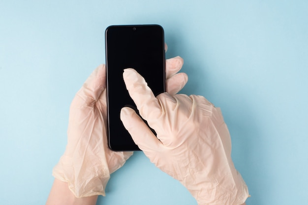 Mikroby na koncepcji smartfona. Pov top overhead zbliżenie widok zdjęcia rąk w rękawiczkach pisania SMS-ów na telefonie na białym tle niebieskim tle