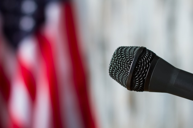 Zdjęcie mikrofon na tle niewyraźne flagi. mikrofon obok flagi ameryki. sprzęt jest gotowy do mowy. wiadomości dla narodu.