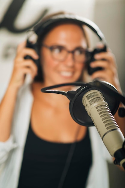 Mikrofon studyjny w ostrości Młoda prezenterka talk show z słuchawkami w tle