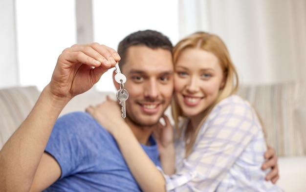 miłość, ludzie, nieruchomości, dom i koncepcja rodziny - uśmiechnięta para pokazująca klucze na tle salonu