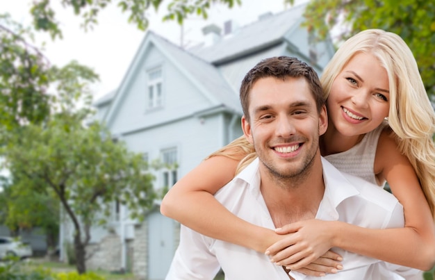 miłość, ludzie, nieruchomości, dom i koncepcja rodziny - uśmiechnięta para przytulająca się na tle domu