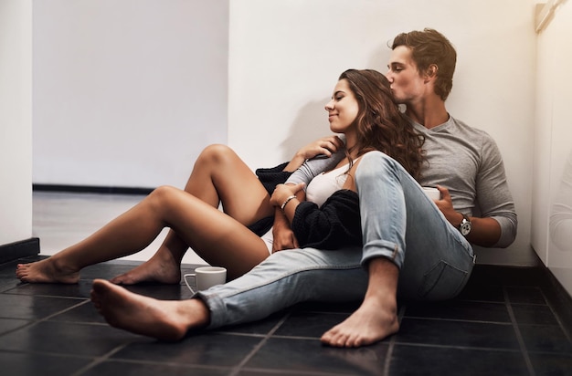 Miłość zmienia dom z miejsca w osobę Ujęcie czułej młodej pary siedzącej na podłodze w kuchni