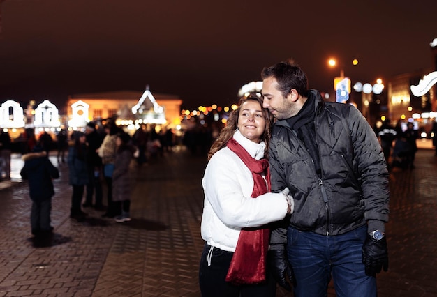 Miłości para spaceruje po mieście wieczorem Bożego Narodzenia w zimie.