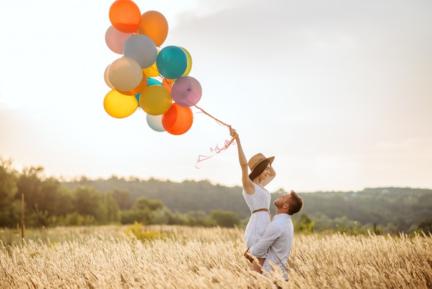 Miłości para z balonami przytula w polu żyta. Ładna kobieta na letniej łące