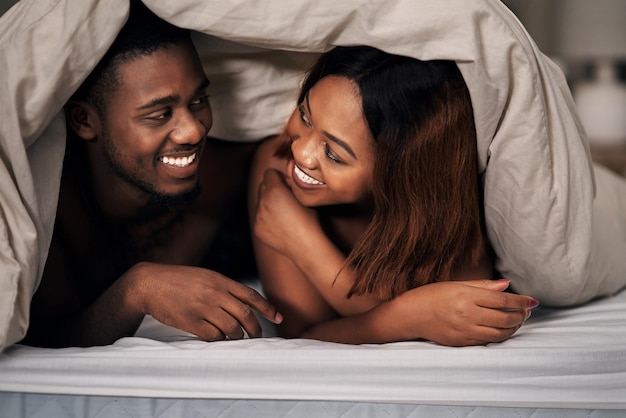 Miłośnicy pod przykrywką Przycięte zdjęcie czułej młodej pary leżącej pod kołdrą na łóżku w domu