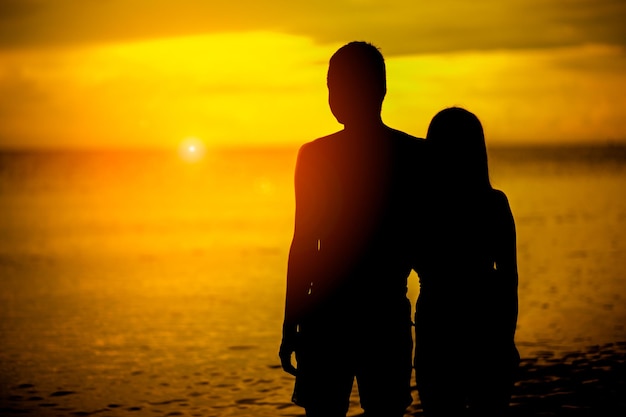 Miłośnicy sylwetki na plaży z zachodem słońca Zakochana para ma romantyczne chwile czułości o zachodzie słońca koncepcja miłości i walentynek