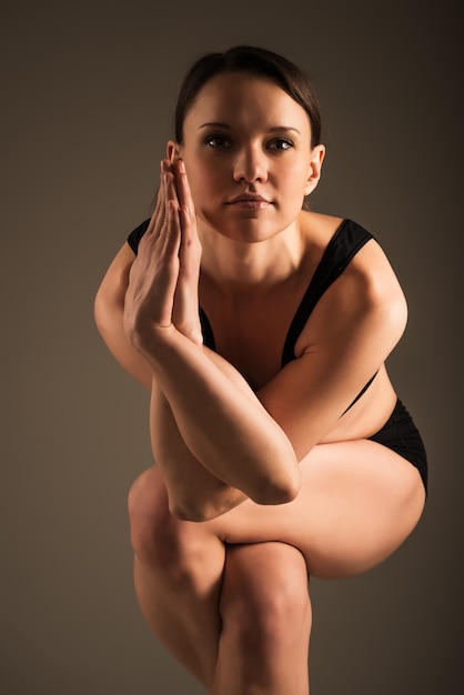 Miłośnik jogi robi Garudasana na ciemnym tle