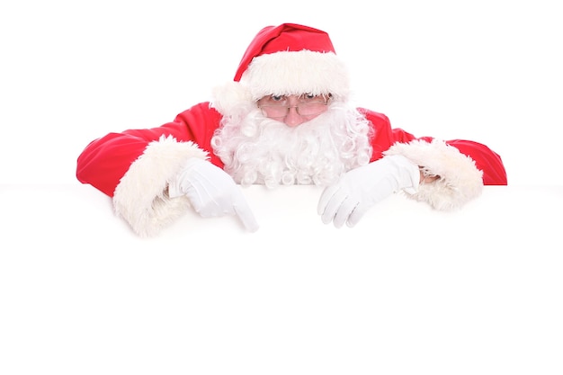 Miły Mikołaj patrząc zza pustego znaku na białym tle z miejsca kopiowania.