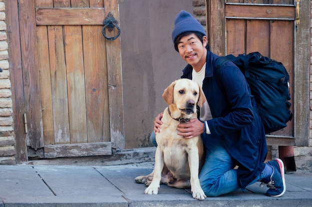 Miły turysta z Korei z plecakiem i psem na ulicy.