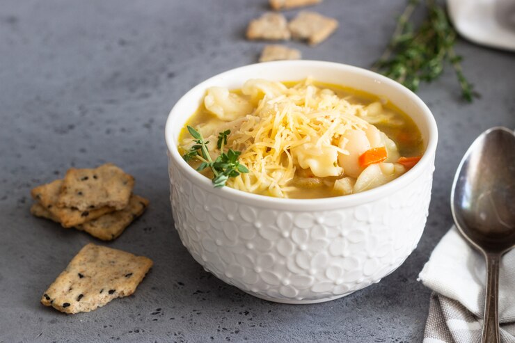 Zdjęcie minestrone z makaronem i białą fasolą polane tymiankiem i podawane z krakersami