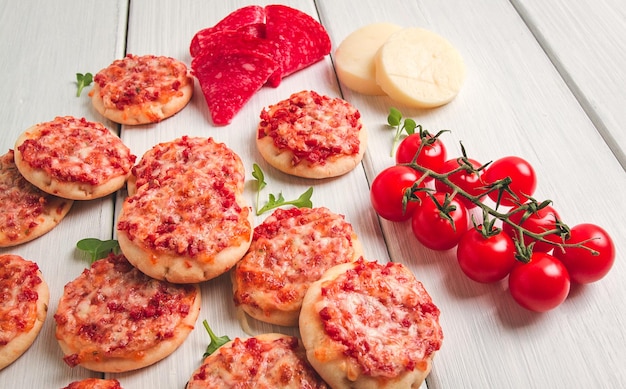 Mini pizze salami z serem mozzarella na białym blacie widok bez ludzi