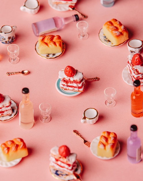 Miniaturowe ciasta i napój na różowym tle