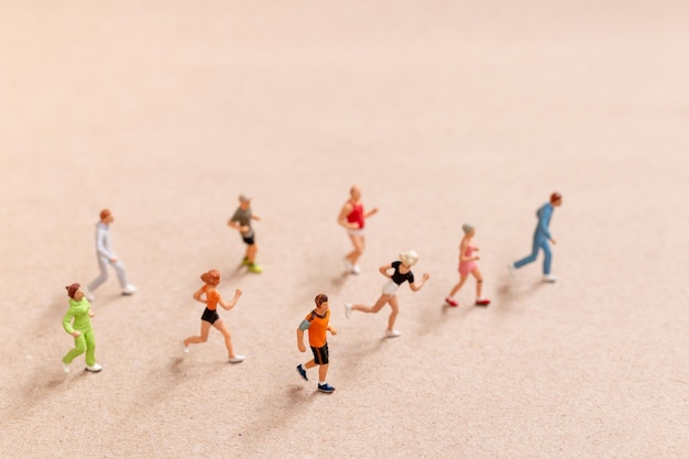 Miniaturowe osoby ćwiczące podczas biegania w grupie po plaży