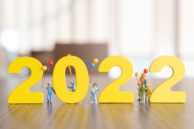 Zdjęcie miniaturowe osoby szczęśliwa rodzina trzyma balon na białym numerze 2022, koncepcja szczęśliwego nowego roku