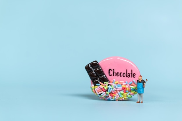 Miniaturowe osoby Szef kuchni z ciasteczkami czekoladowymi na niebieskim tle Koncepcja światowego dnia czekolady