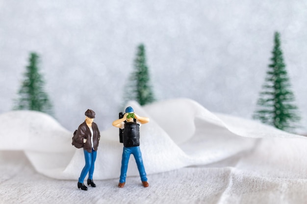 Miniaturowi ludzie Backpacker Travel w zimie
