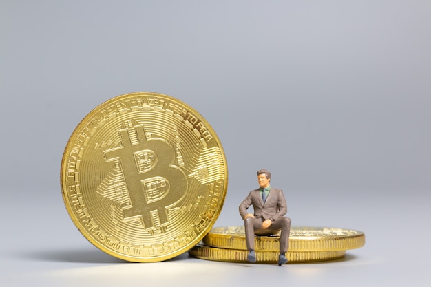 Miniaturowi ludzie Biznesmen siedzi na monetach Bitcoin