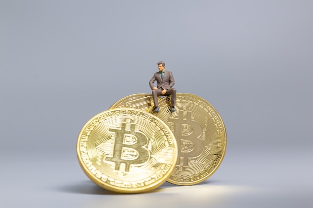Miniaturowi ludzie Biznesmen siedzi na monetach Bitcoin