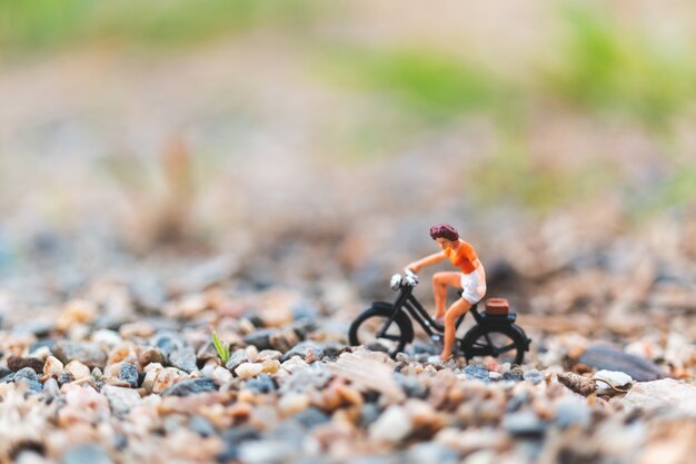 Miniaturowi ludzie: podróżnicy jadący rowerem po piasku
