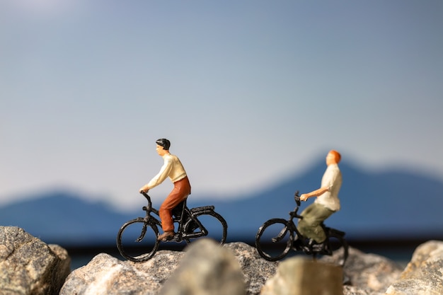 Miniaturowi ludzie: Podróżnik z rowerem jadącym po skale, koncepcje Travel i Adventure.