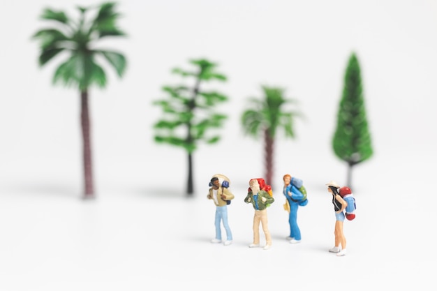 Miniaturowi ludzie: Podróżujący z plecakiem idącym po whitebackground,