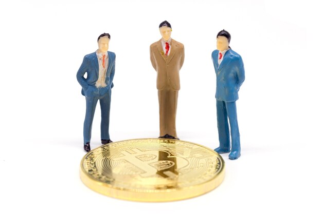 Miniaturowy biznesmen i Bitcoin na białym tle