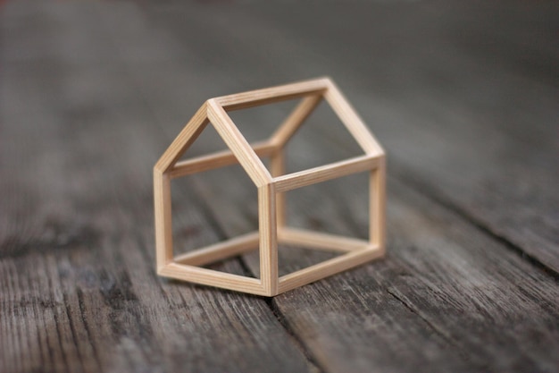 Miniaturowy model domu z drewnianą ramą na rustykalnym tle drewna