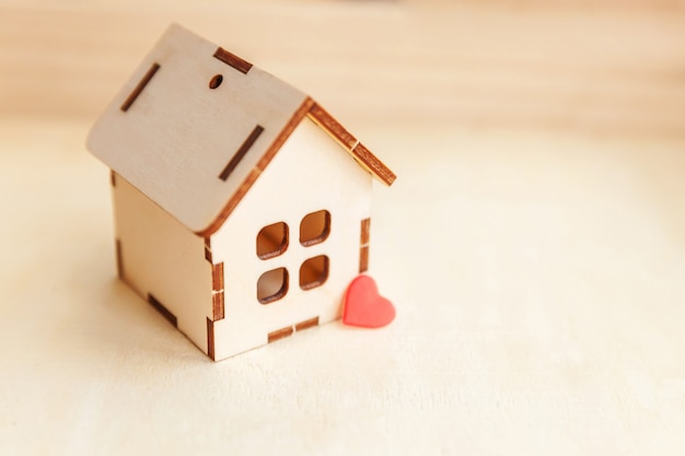 Miniaturowy model domu zabawka z czerwonym sercem na tle drewniane. Eco Village streszczenie tło środowiska. Nieruchomość hipoteki majątku ubezpieczenia słodkiego sen domowy ekologii pojęcie