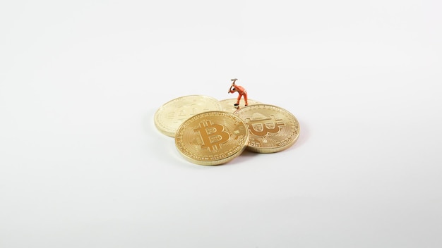 Miniaturowy robotnik wydobywający bitcoiny na białym tle mała figurka trzymająca motykę kopiącą więcej monety kryptowaluty Bitcoin