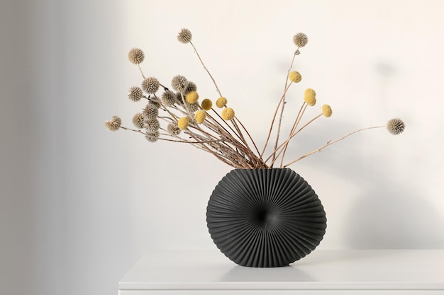 Minimalistyczna kompozycja suszonych okrągłych kwiatów w ceramicznym wazonie jako dekoracja domu