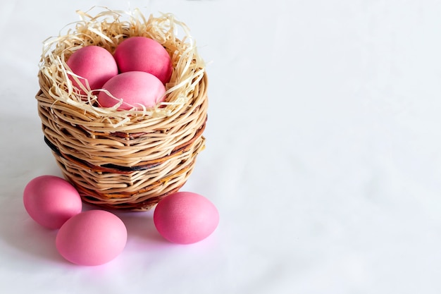Minimalistyczna kompozycja wielkanocna z wiklinowym koszem i różowymi jajkami