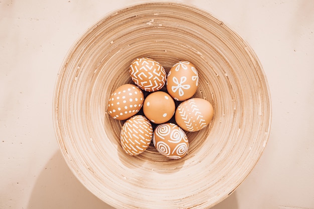 Minimalistyczna kompozycja. Wielkanocni jajka na talerzu. Styl ekologiczny. Ciepłe pastelowe odcienie. Widok z góry